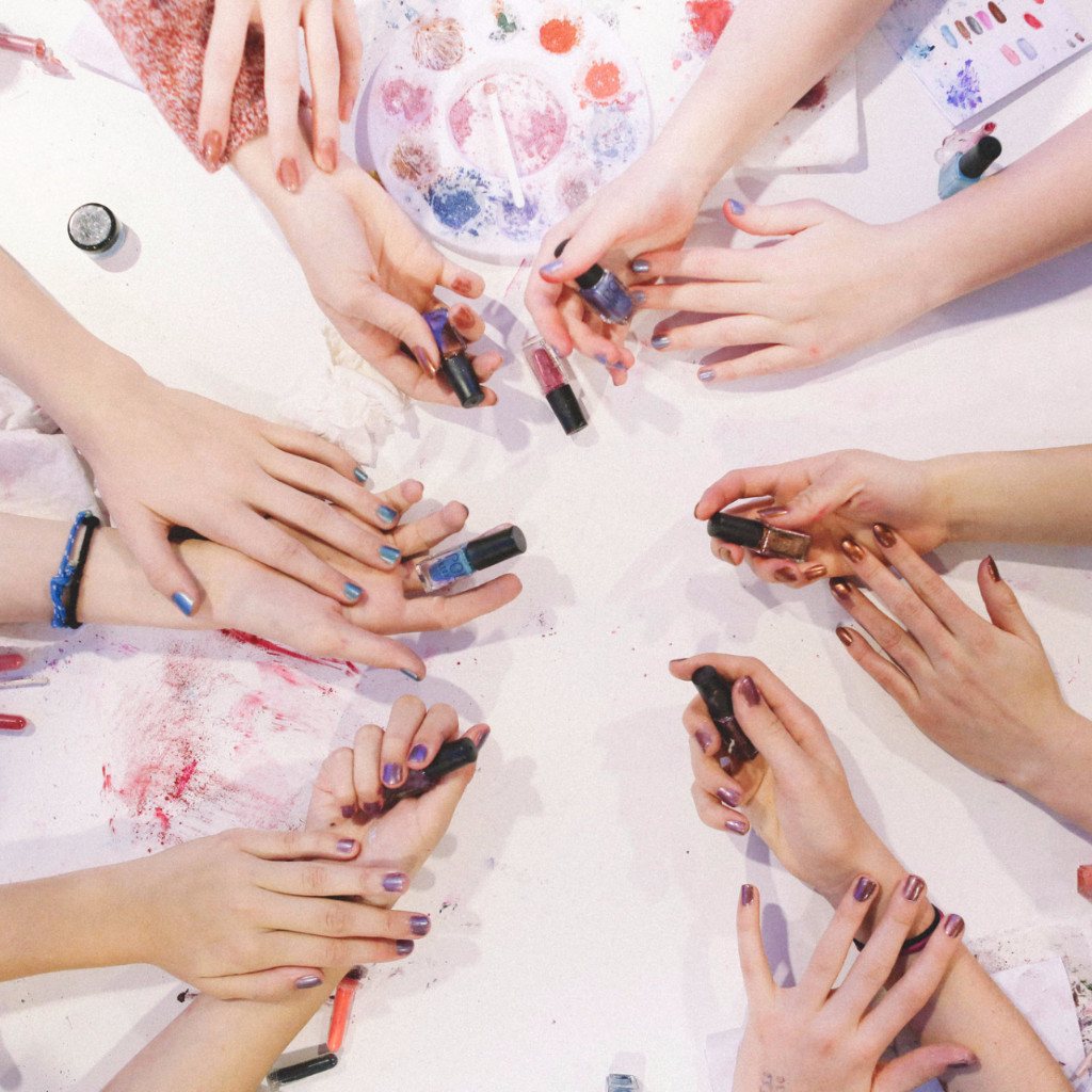 Girls hands holding completed DIY nail polish over table with Mixify Beauty DIY nail polish kits