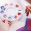 Girls stirring color in palette of nail polish colored powders