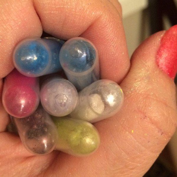 Close up of hand with coral nails holding yellow, blue, red, purple, white, green micas in tubes